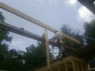 Carpenter setting a ridge beam over a new addition frame — Ice Dam Removal by Roofing Brothers in Cummings