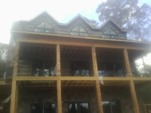 Dormers and porch framing on a large log home under construction — Roof Coating work by our crew in Cummings