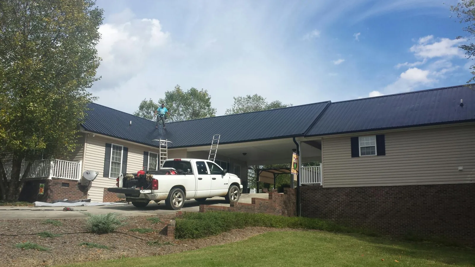 Black metal roof over a home and attached breezeway with ladders set in Cummings