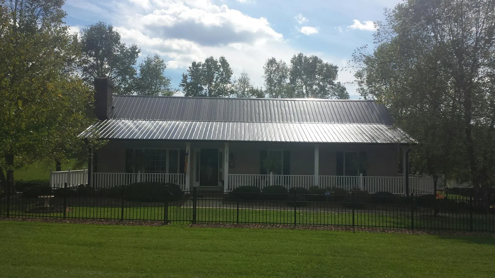 Gray metal roof on a brick ranch with a full width front porch — Gutter Guard Installation work by our crew in Cummings