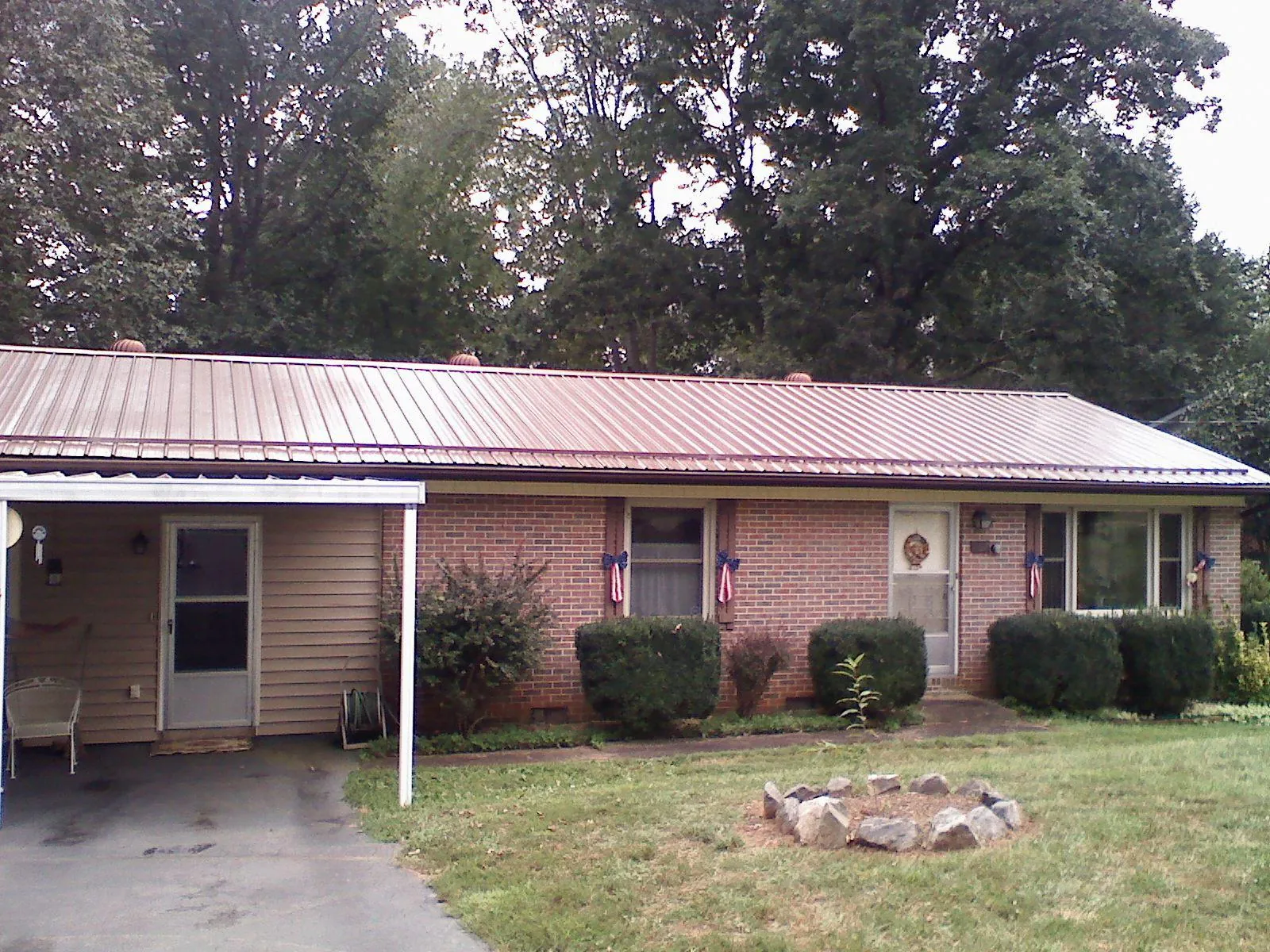 Bronze metal roof and carport on a brick ranch home — Roof Repair work by our crew in Cummings